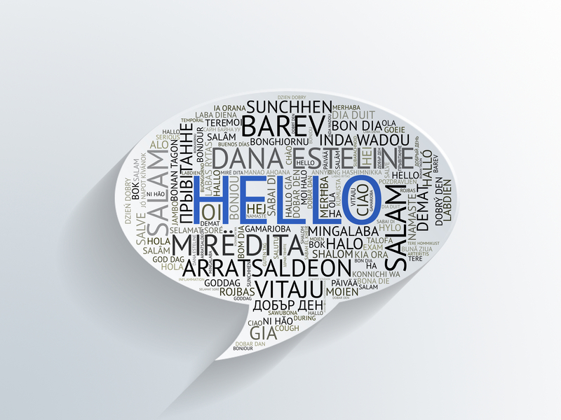 A white speech bubble with Hello in the center in blue surrounded by Hello in many other languages in black